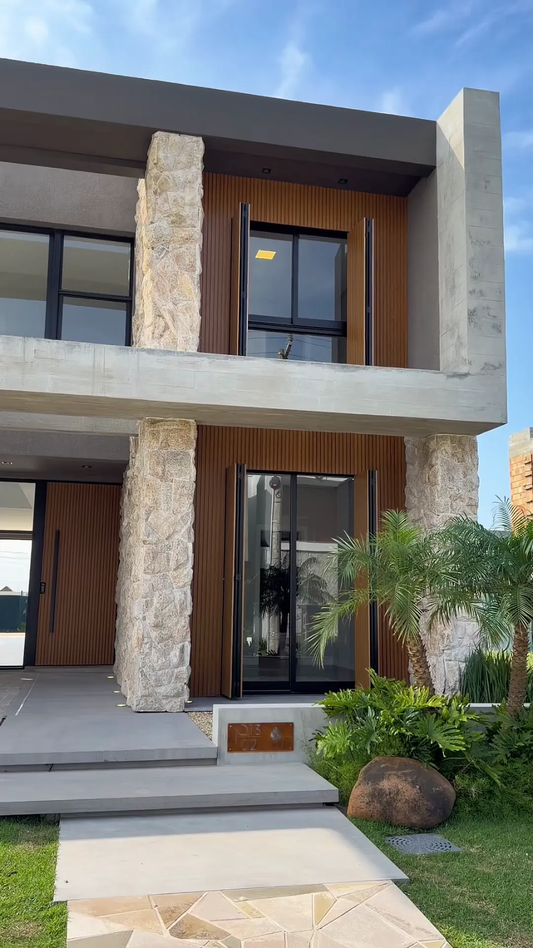 Fachada frontal da Casa Zen, com pedra moledo e alumínio amadeirado